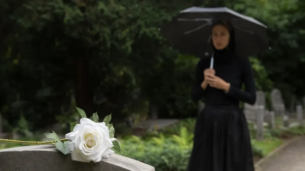 Donna con un ombrello nero durante un funerale piovoso